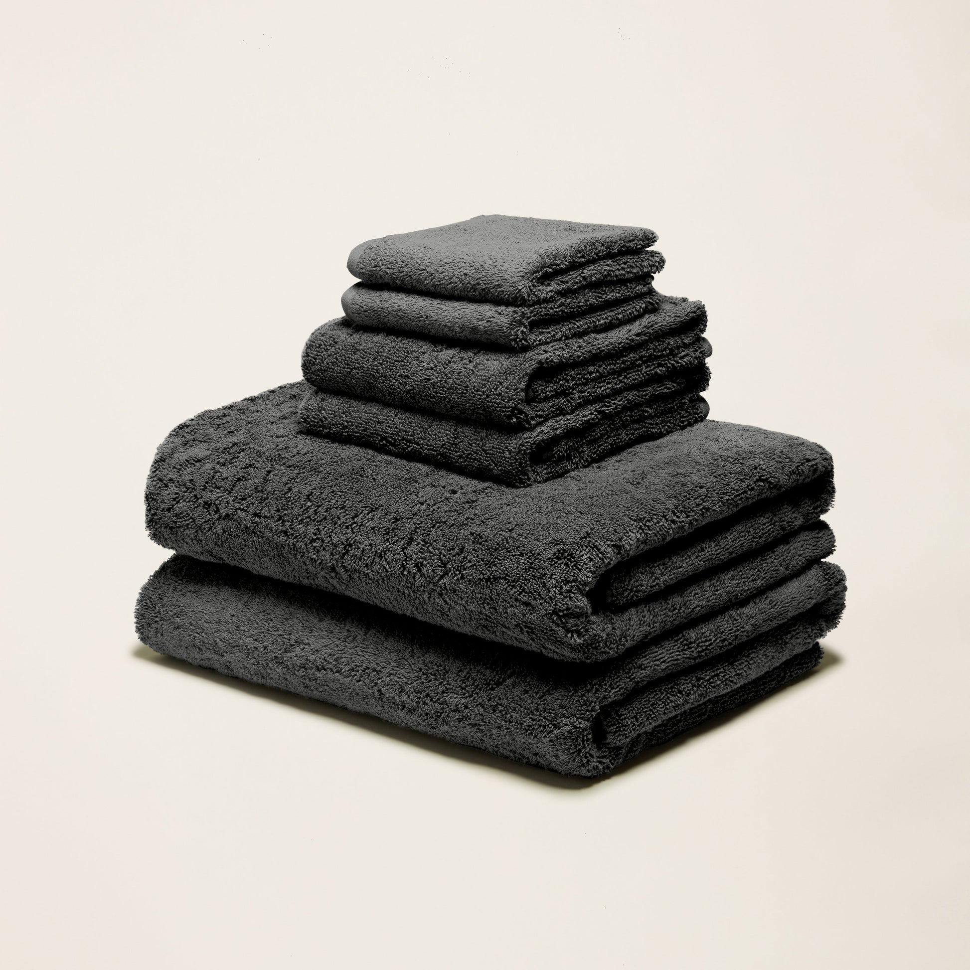 Dark gray cotton towels folded in a stack, plush terry texture
