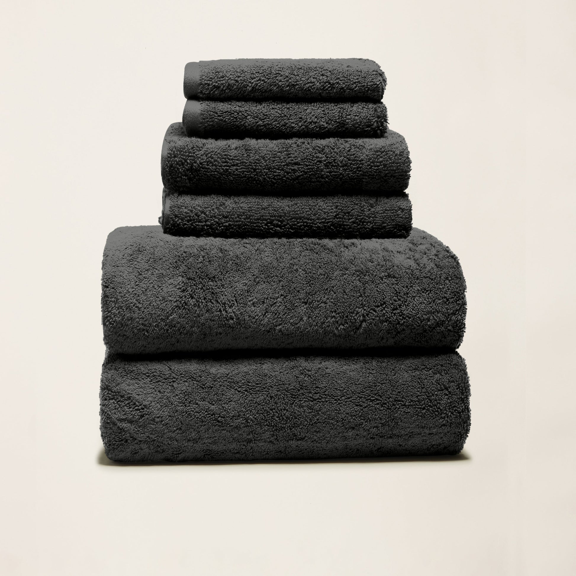 Dark charcoal cotton towels folded in a stack, plush looped texture