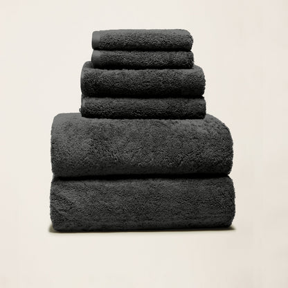 Dark charcoal cotton towels folded in a stack, plush looped texture