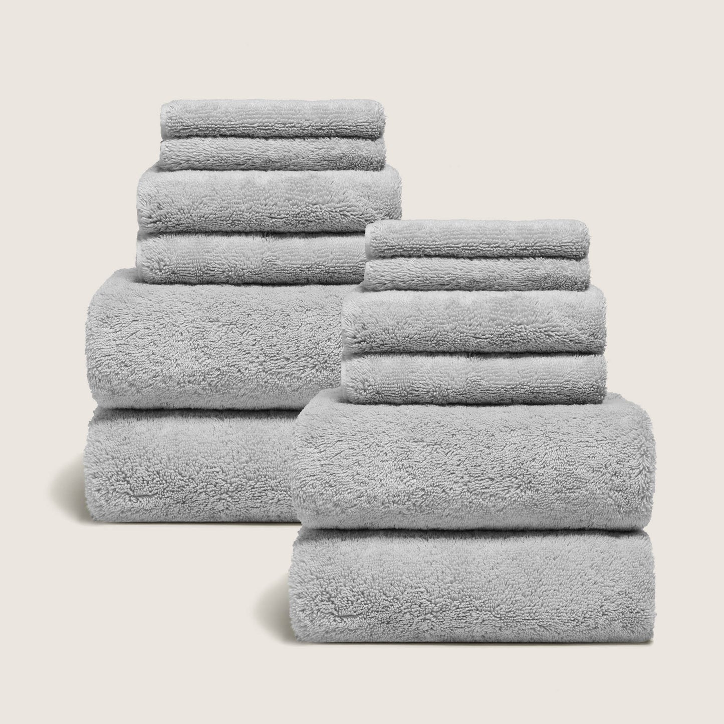 Light gray cotton towel set with plush looped texture, stacked with folded tiers