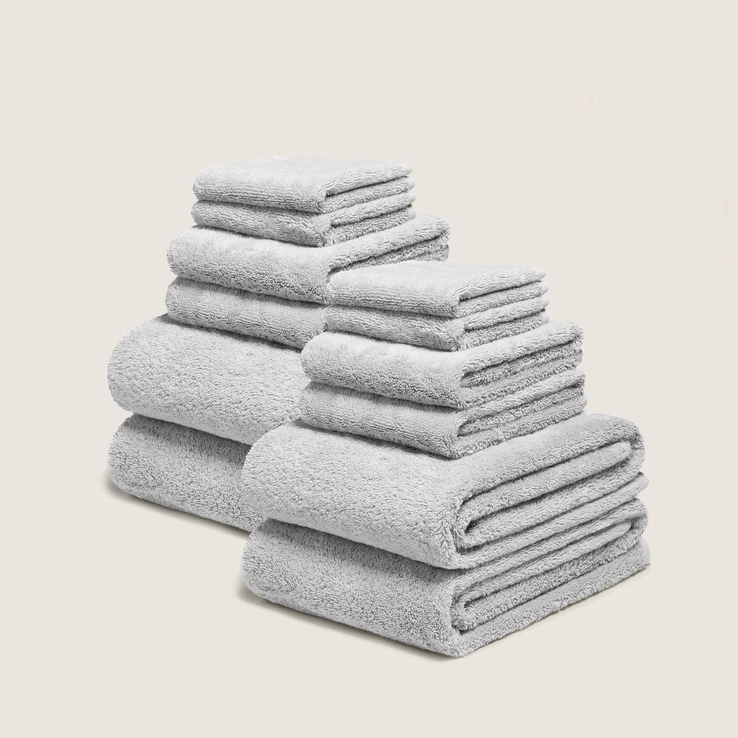 Light gray cotton towel set with plush looped texture, stacked in folded layers
