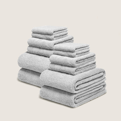 Light gray cotton towel set with plush looped texture, stacked in folded layers
