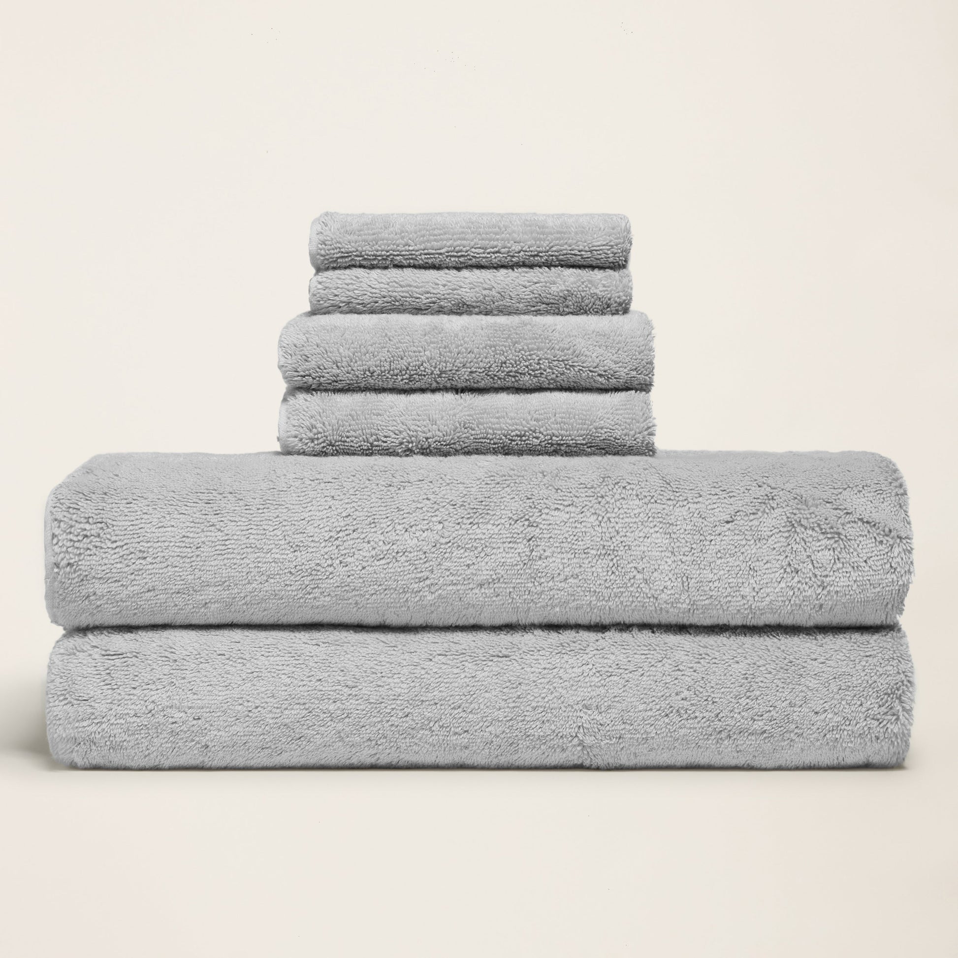 Light gray cotton towels folded in a stack, thick plush terry surface