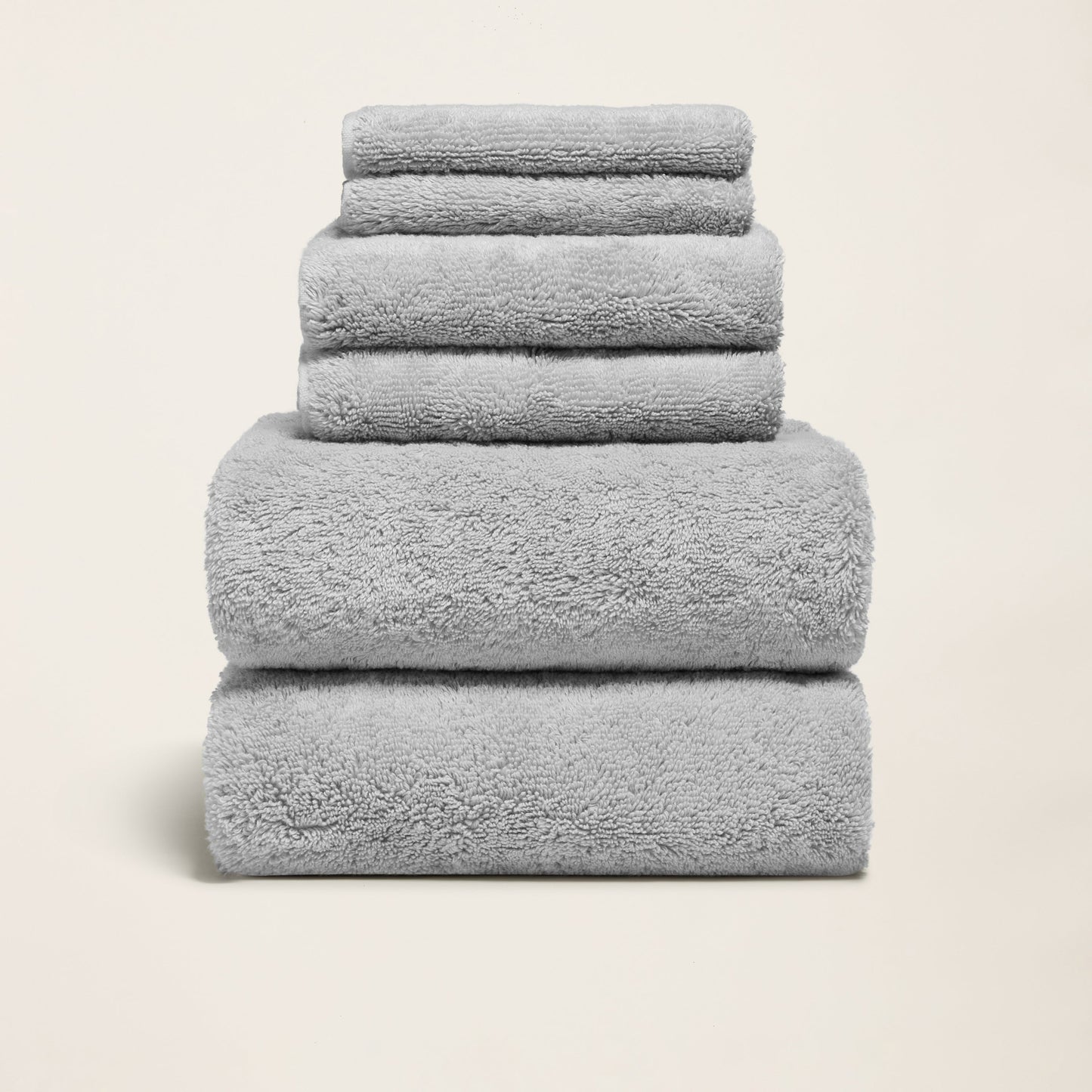 Light gray cotton towels folded in a stack, soft plush terry texture