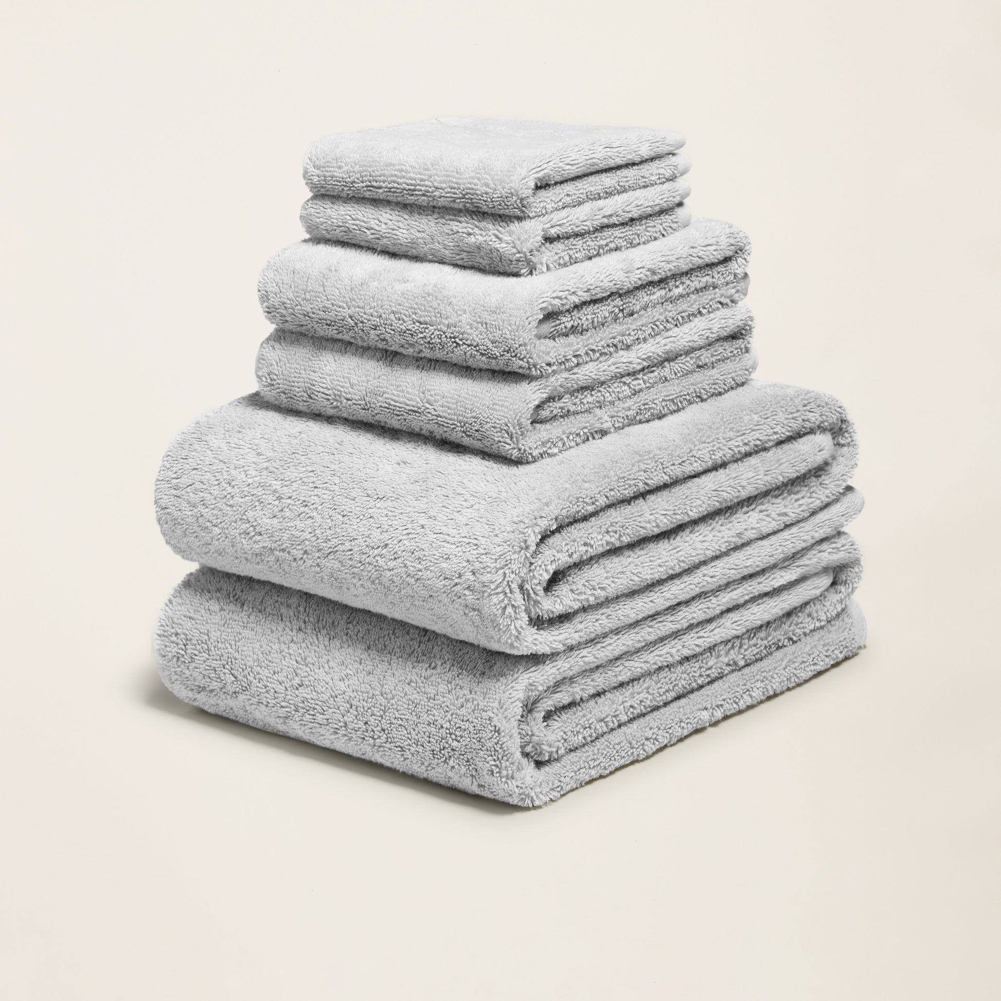 Pale gray cotton towels folded in a stack, plush terry weave