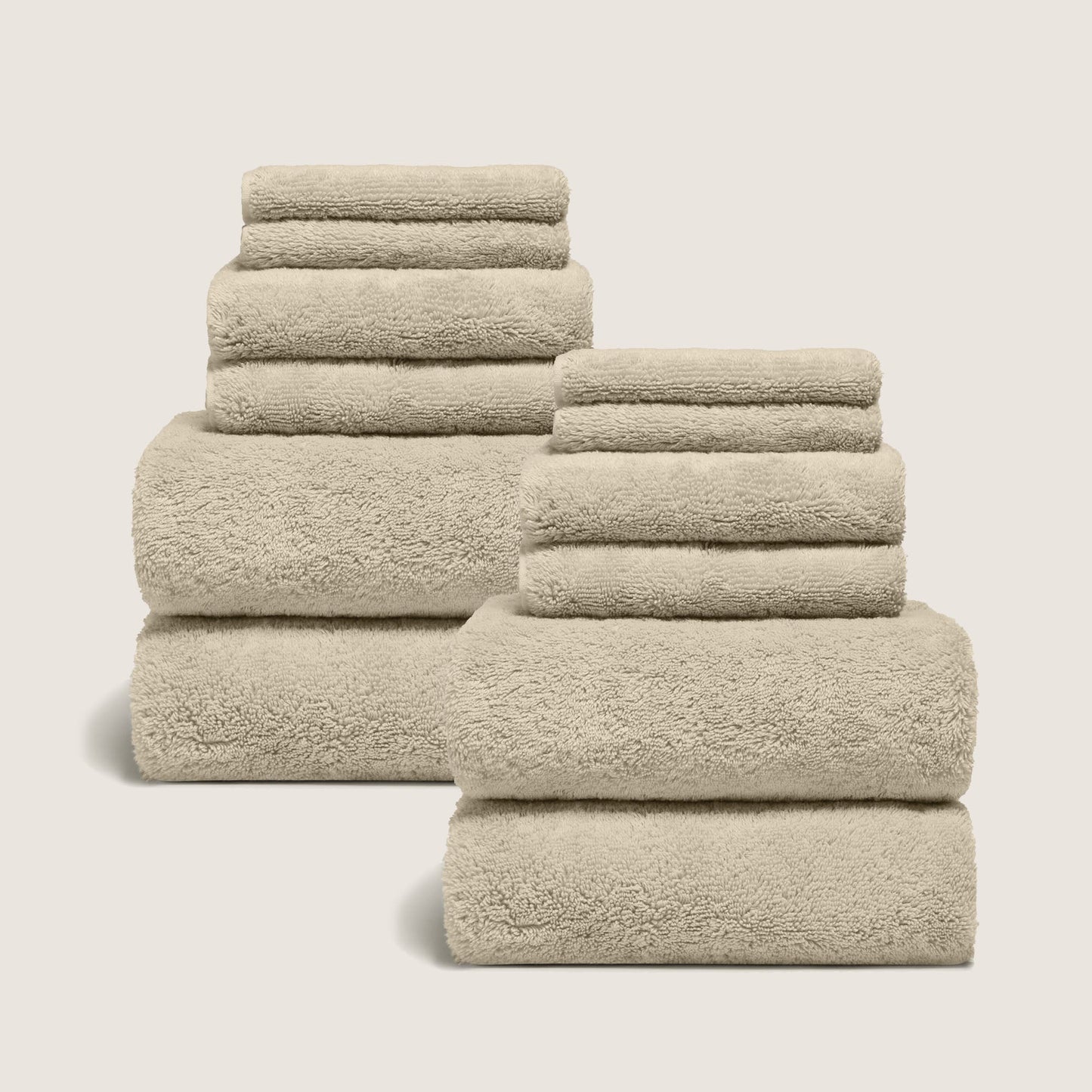 Sand-colored cotton towel set with plush looped texture, stacked neatly