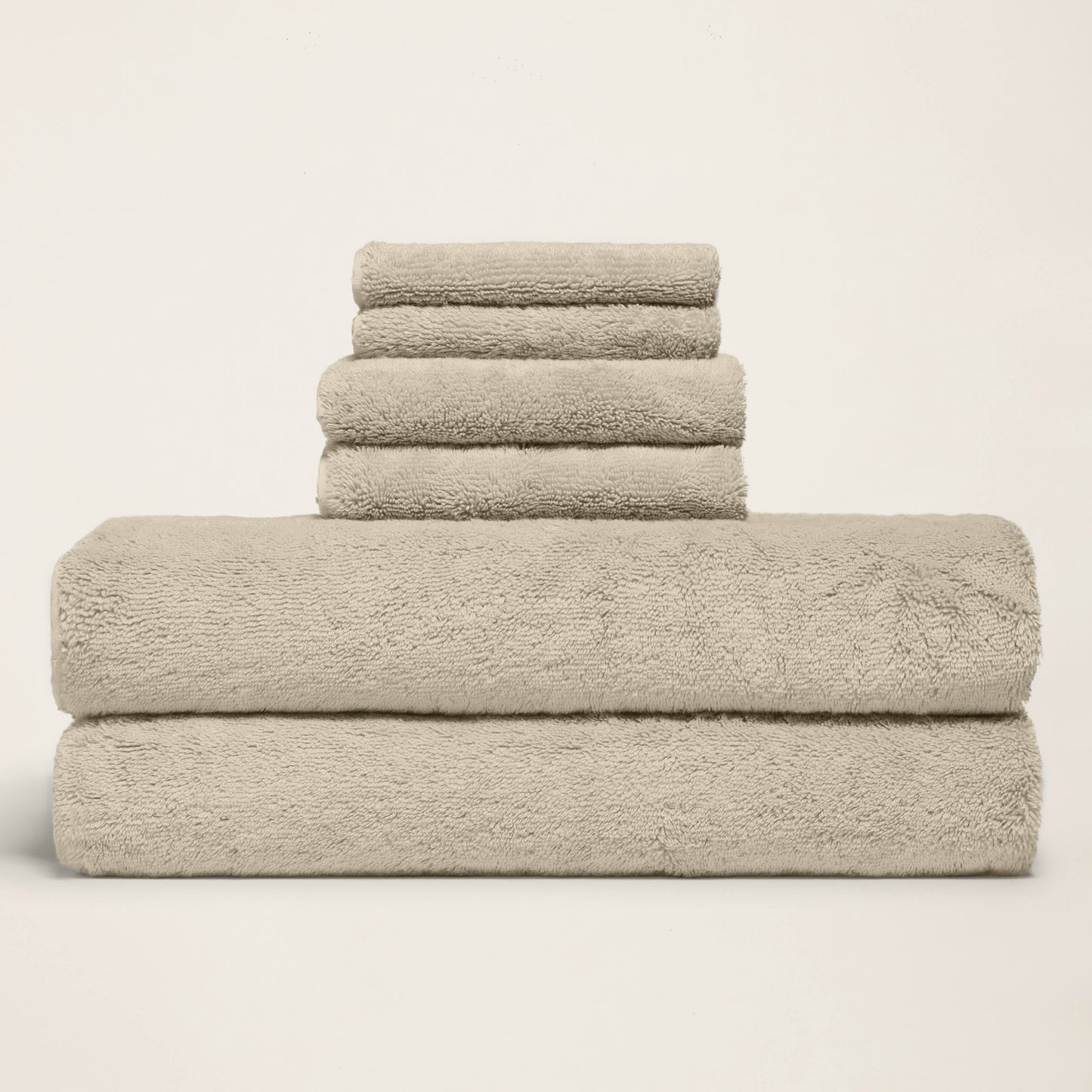 Folded towel set with one long towel stacked under three, light sand terry.