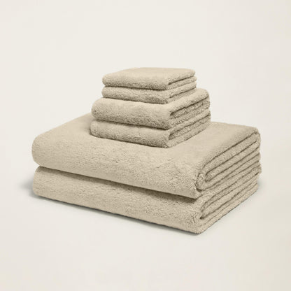 Stacked plush towels, light sand, thick terry loop pile, corner folded.