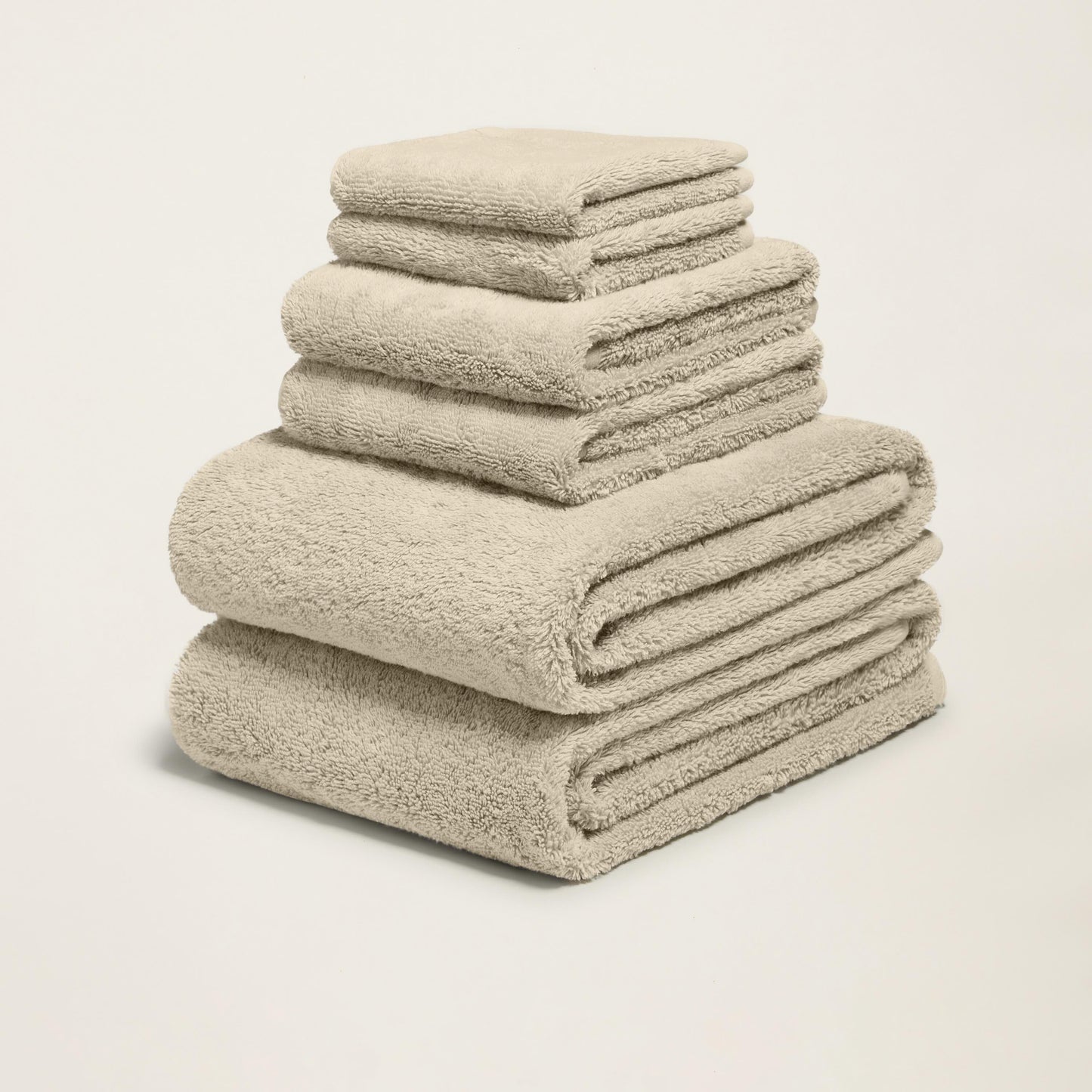 Tower of folded plush towels, light sand, thick terry loop pile.