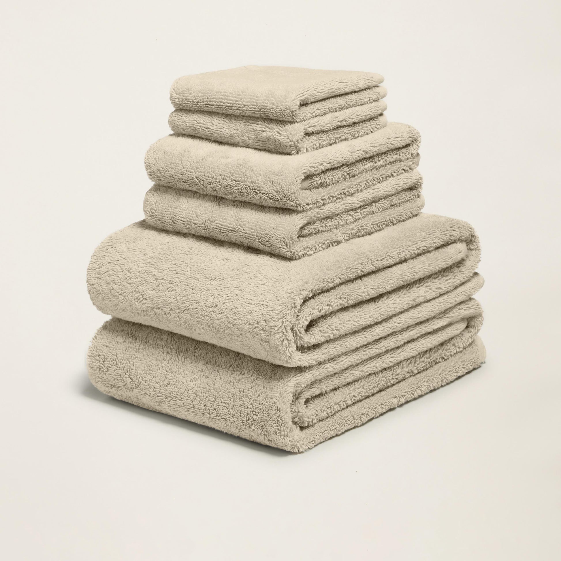 Tower of folded plush towels, light sand, thick terry loop pile.