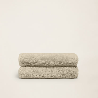 Pair of folded plush towels, light sand, dense terry loop pile.