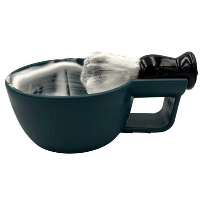 Dark teal shaving bowl with handle and black-tipped brush on the rim