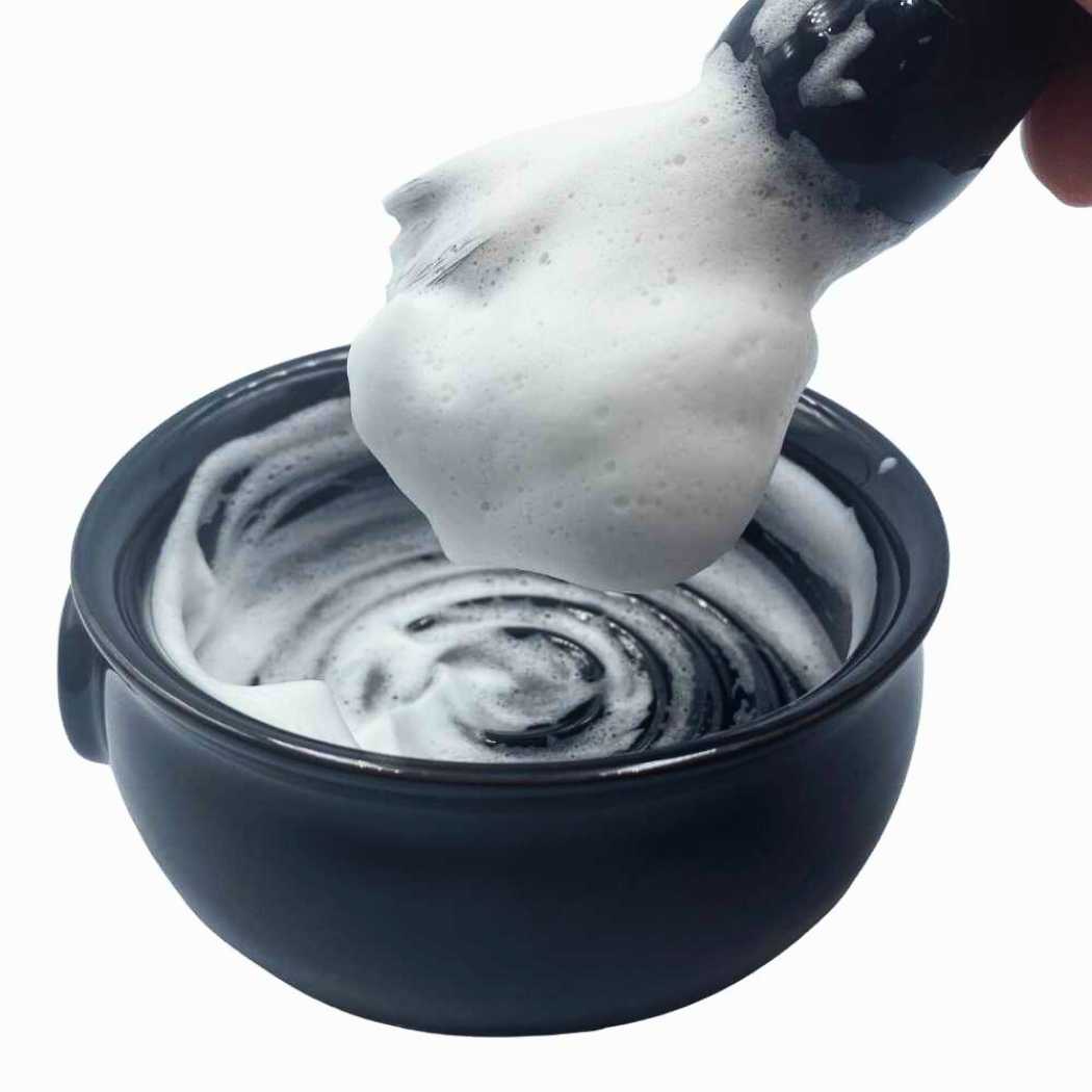 Shaving soap lather in dark bowl, soap scoop with foam