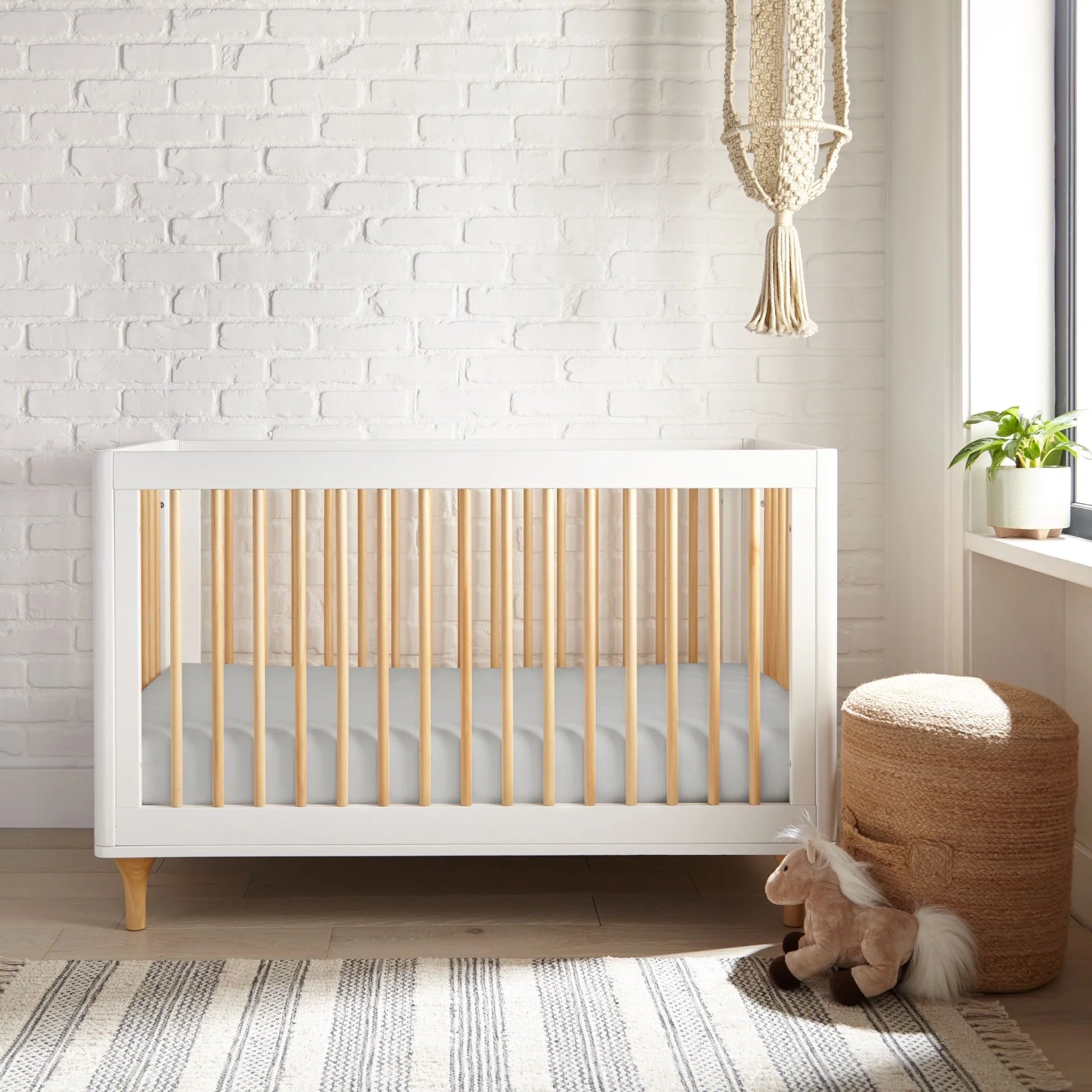 Crib fitted sheet in white, fitted smooth fabric covering the mattress