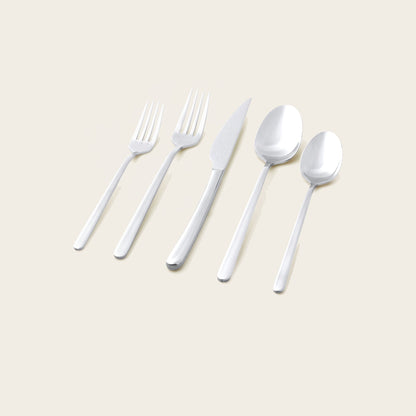 Silver flatware set pieces laid out: forks, knives, and spoons on a light surface