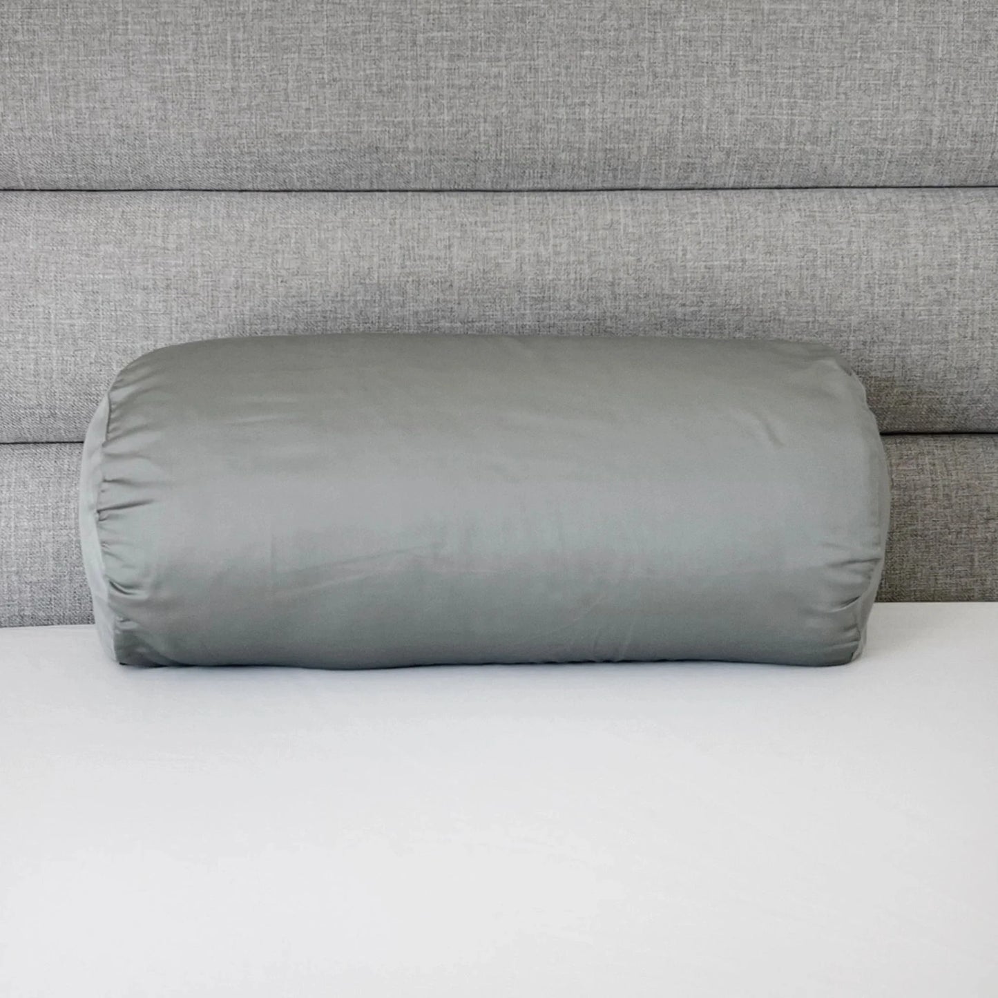 Light gray bolster pillowcase, cylindrical cover with gathered end seam.