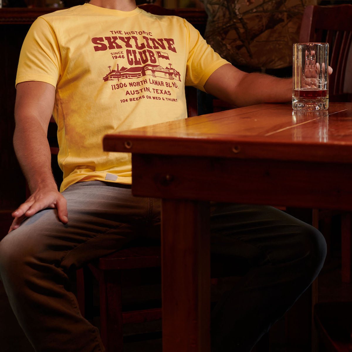 Yellow Skyline Club T-shirt with front graphic worn by a person