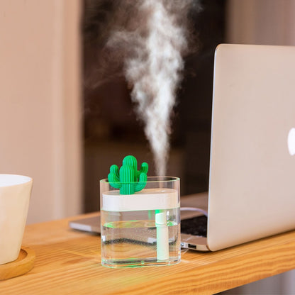 Desktop ultrasonic humidifier with green cactus top, releasing a thick mist plume