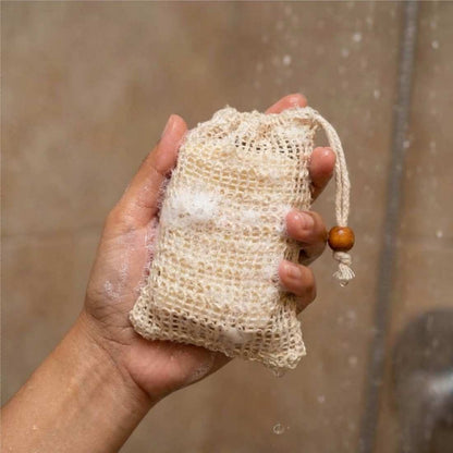 Soap saver bag, beige mesh pouch holding a bar of soap, drawstring with bead