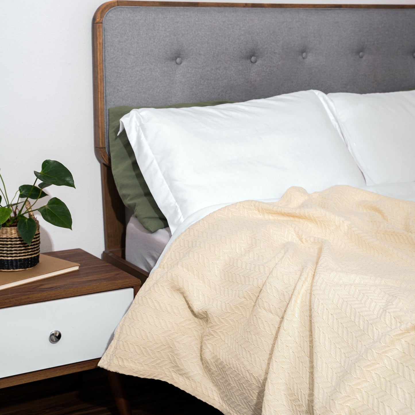Herringbone cotton blanket, light ivory, draped over bedding with chevron knit texture