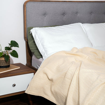 Herringbone cotton blanket, light ivory, draped over bedding with chevron knit texture