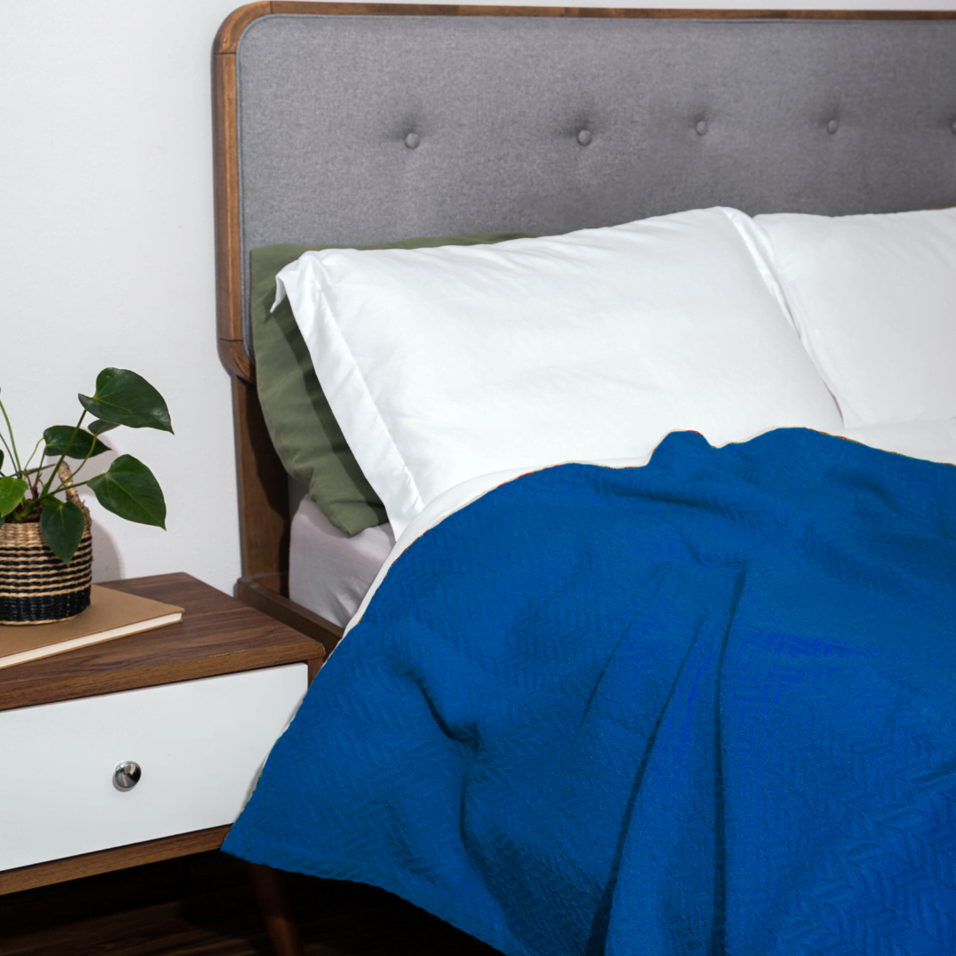 Herringbone cotton blanket, blue, draped over bedding with chevron knit texture
