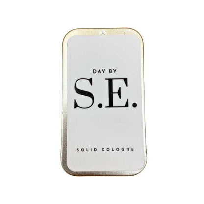 Day by S.E. solid cologne tin, white case with black S.E. logo