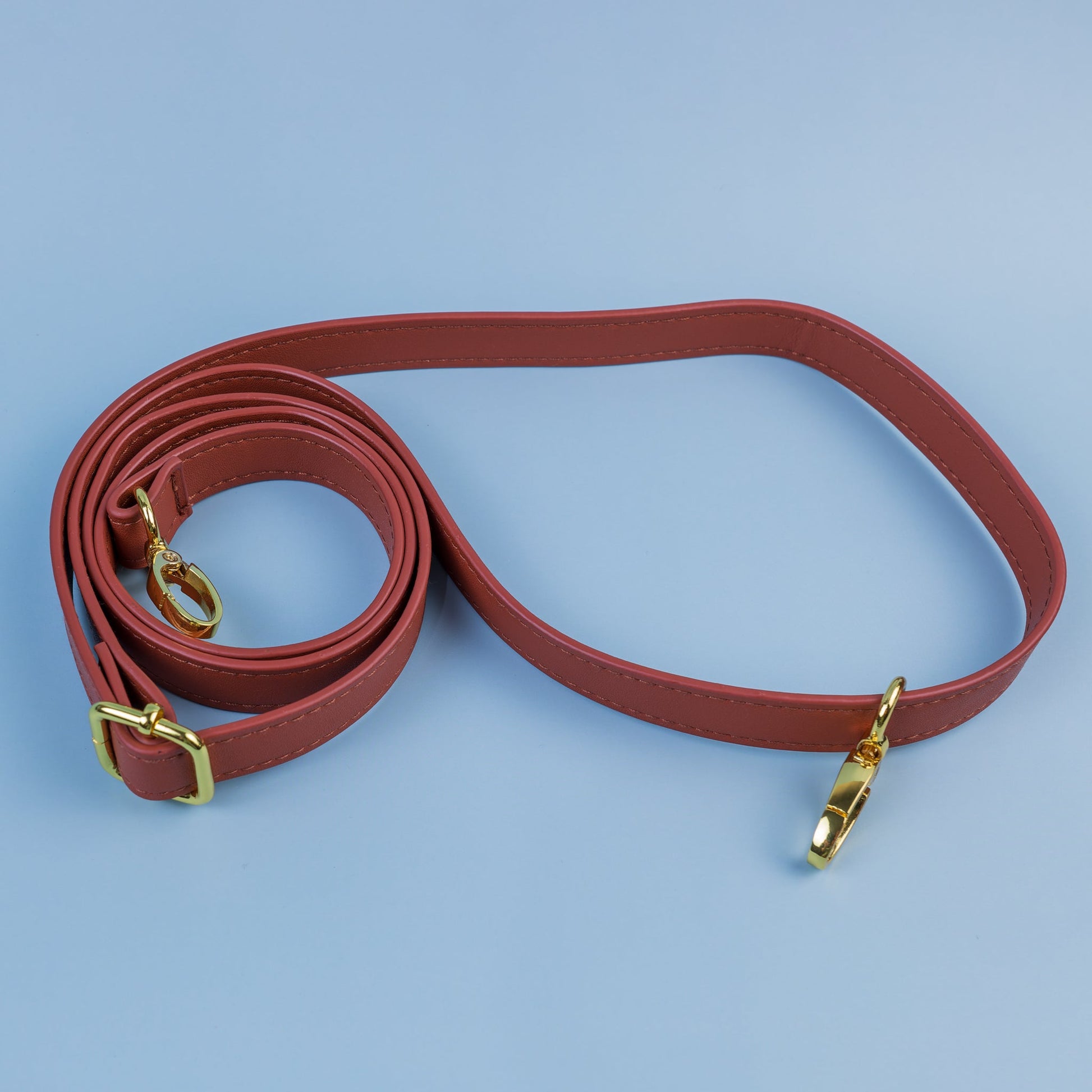 SYB brown crossbody strap with gold clips, laid flat