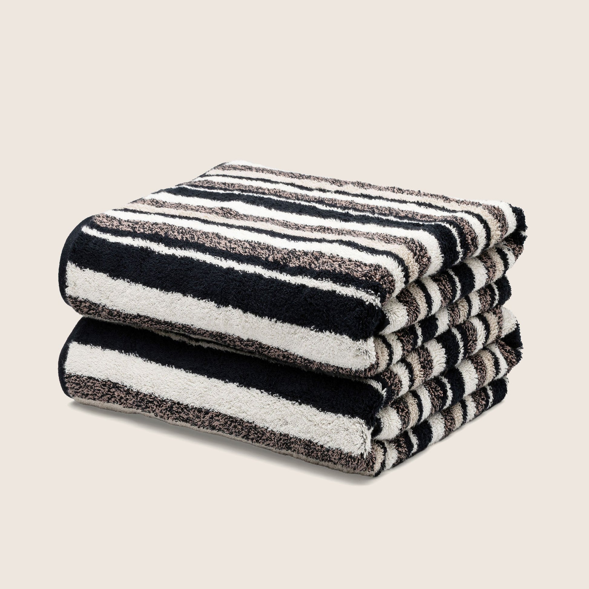 Folded bath towels with dark and white striped design, plush textured terry pile.