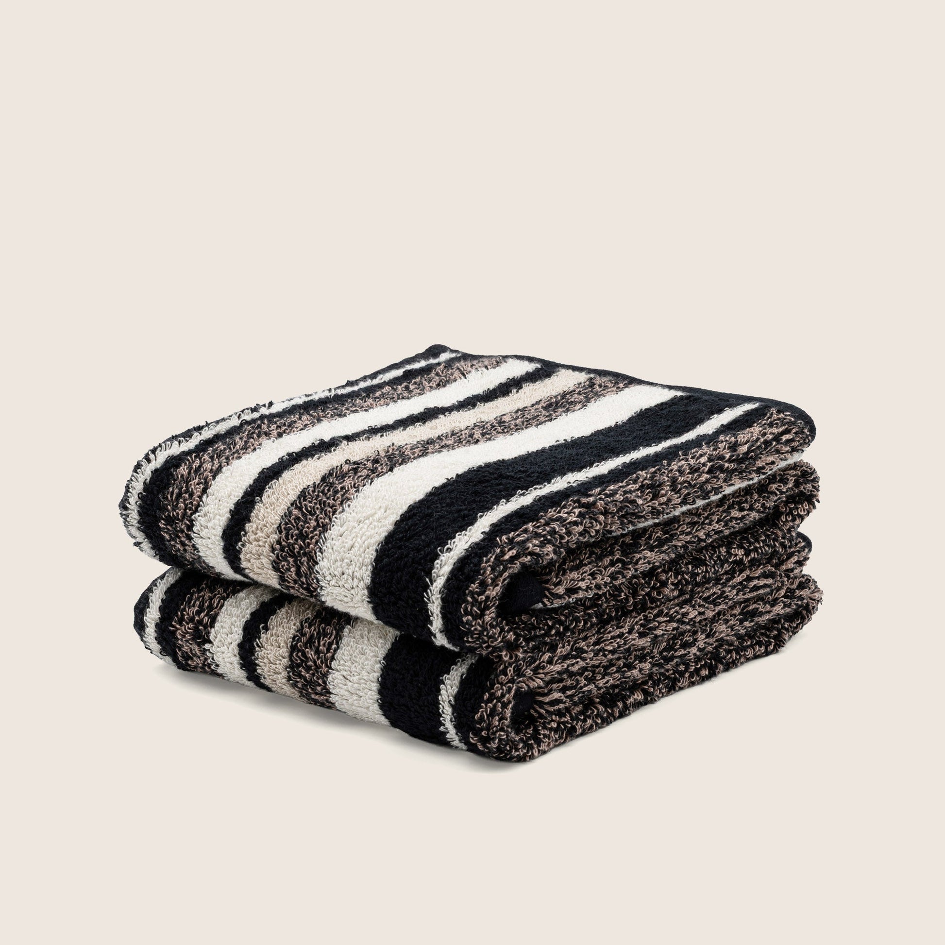 Folded striped towel with bold dark and light bands, plush texture visible at the edge.