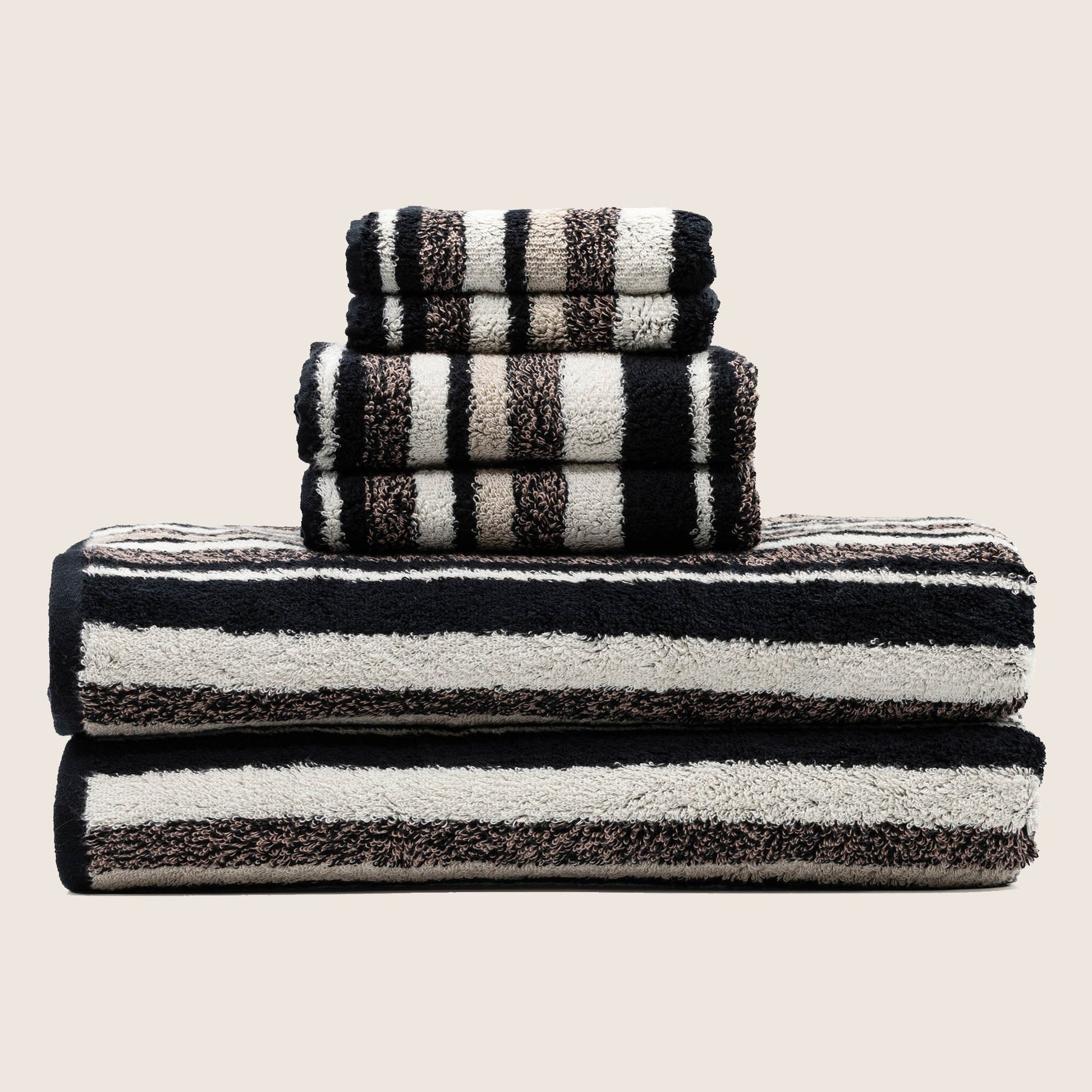 Three folded striped towels in dark and light bands, stacked upright for display.