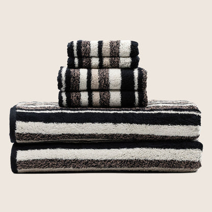 Three folded striped towels in dark and light bands, stacked upright for display.