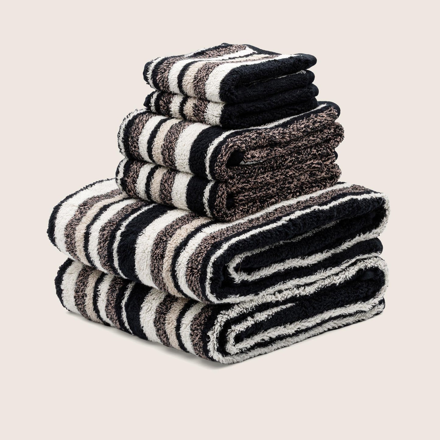 Stack of folded striped towels with dark and light horizontal stripes, thick plush terry pile.