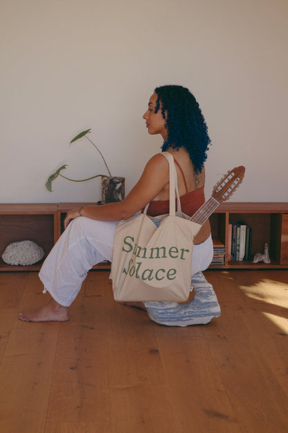 Off-white canvas tote bag with long handles and 'Summer Solace' front text