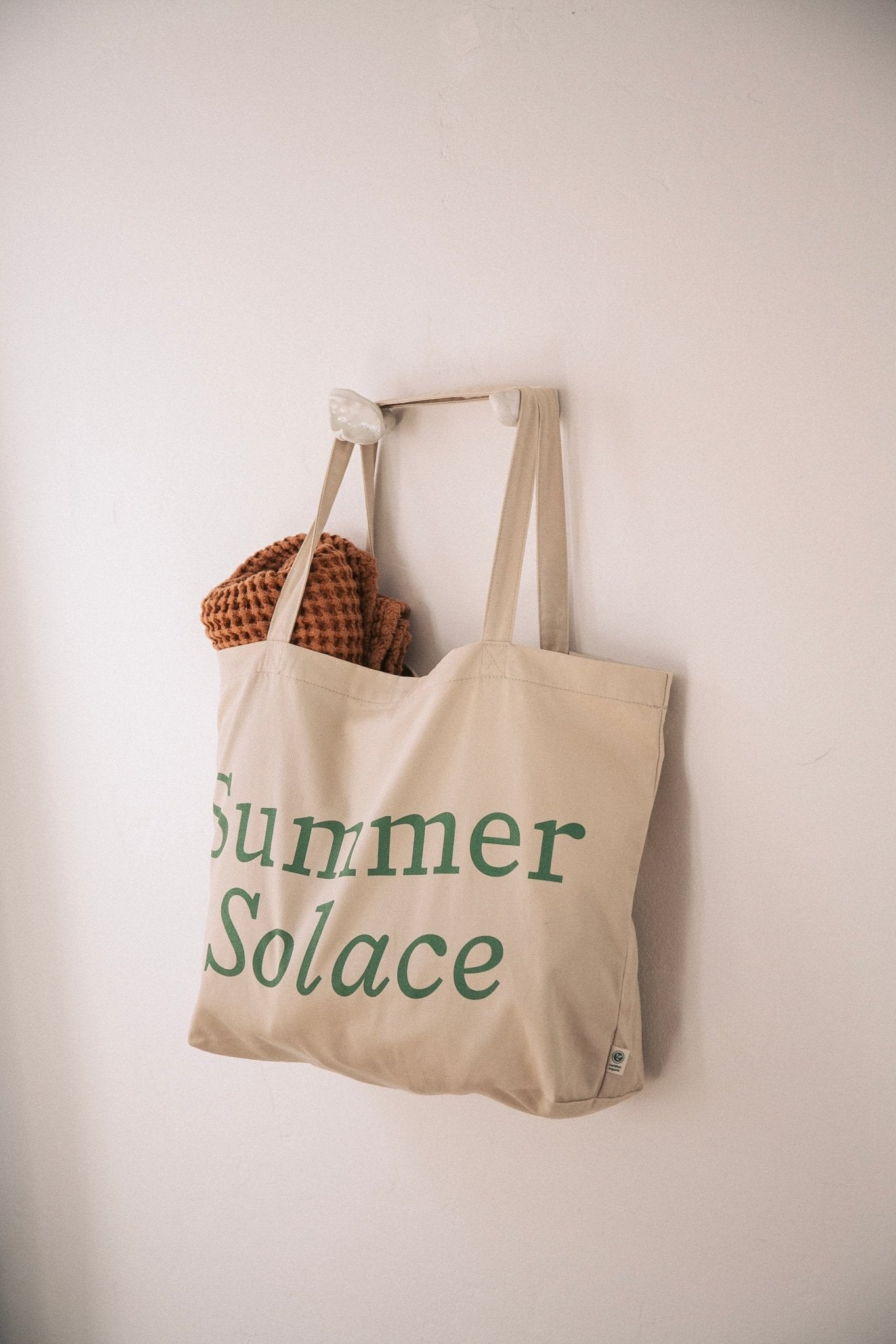 Off-white canvas tote bag with long handles and 'Summer Solace' front text