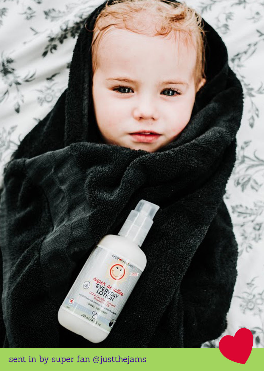 Fragrance-free everyday lotion bottle with pump held by a child wearing a dark hood