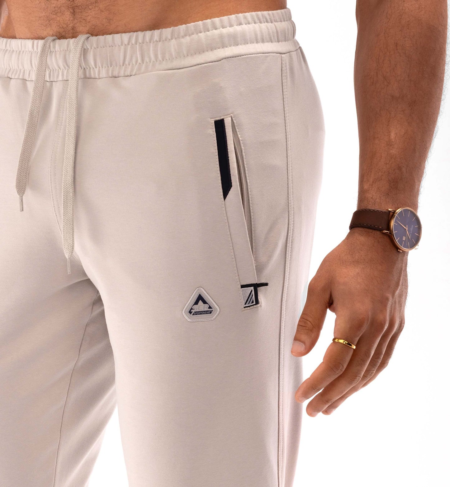 Athletic sweatpants with elastic waistband and drawstring; light khaki with front logo patch.