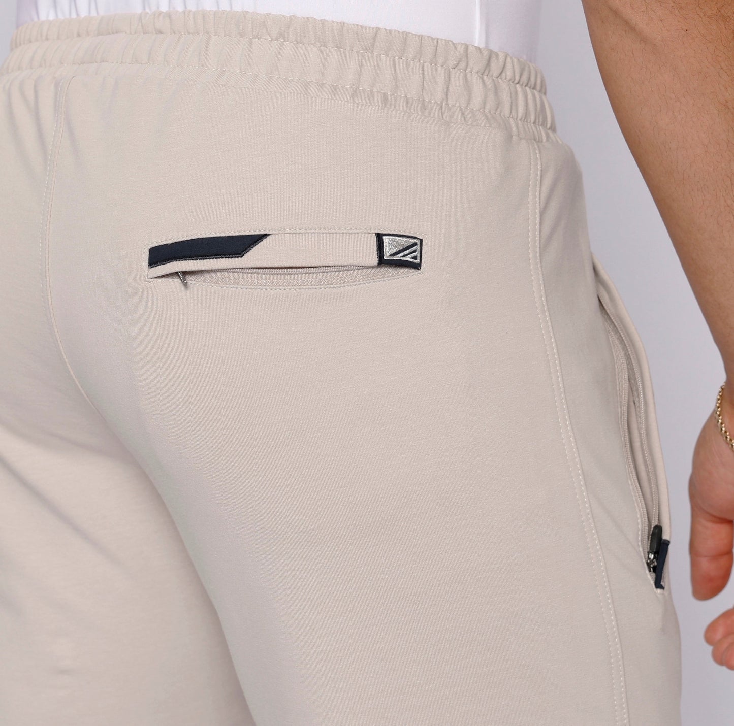 Light beige sweatpants back pocket detail with logo patch and stitching
