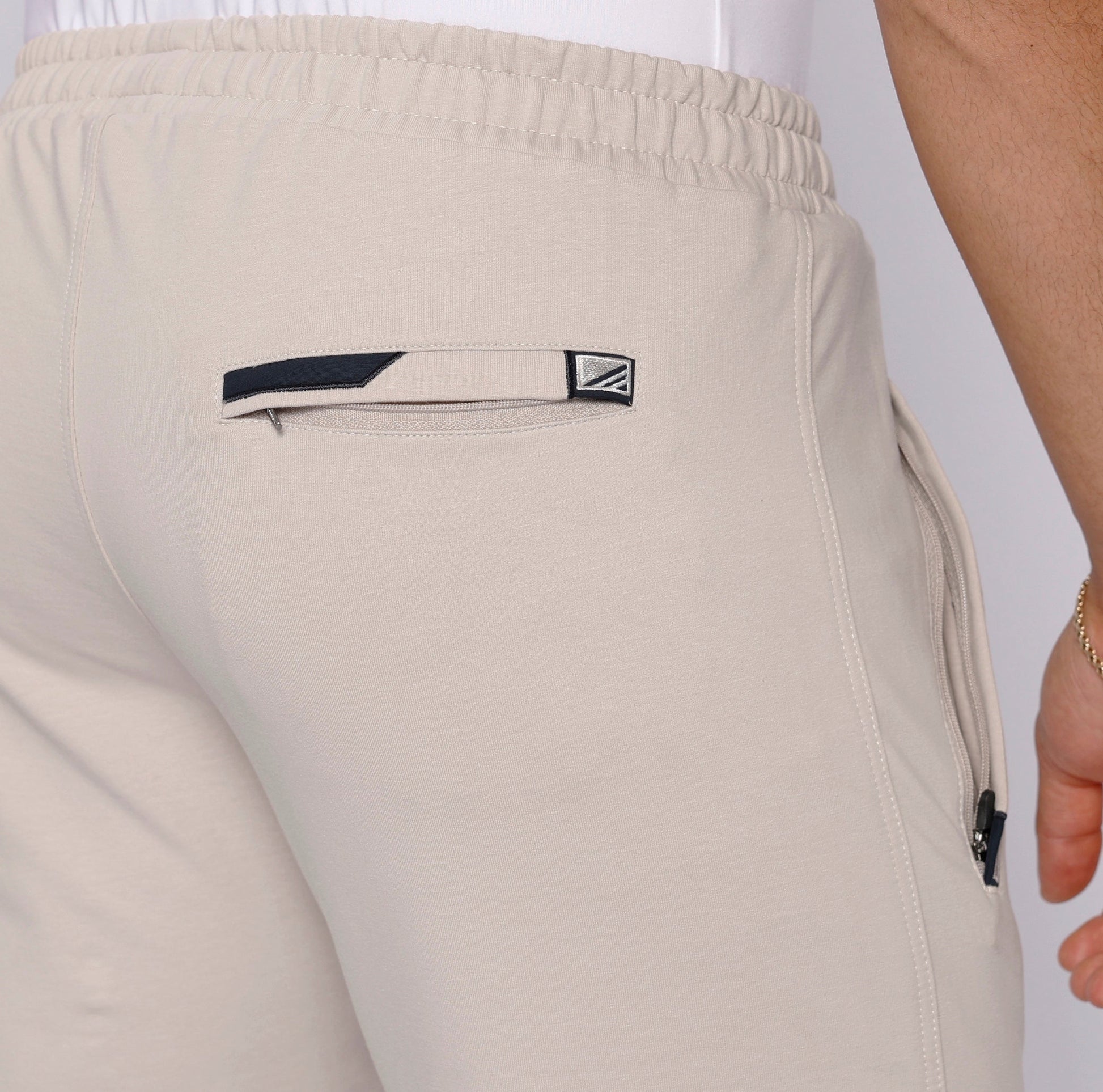 Light beige sweatpants back pocket detail with logo patch and stitching