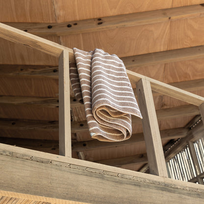 Striped towels draped on wooden loft railing, beige and white plush cotton loops