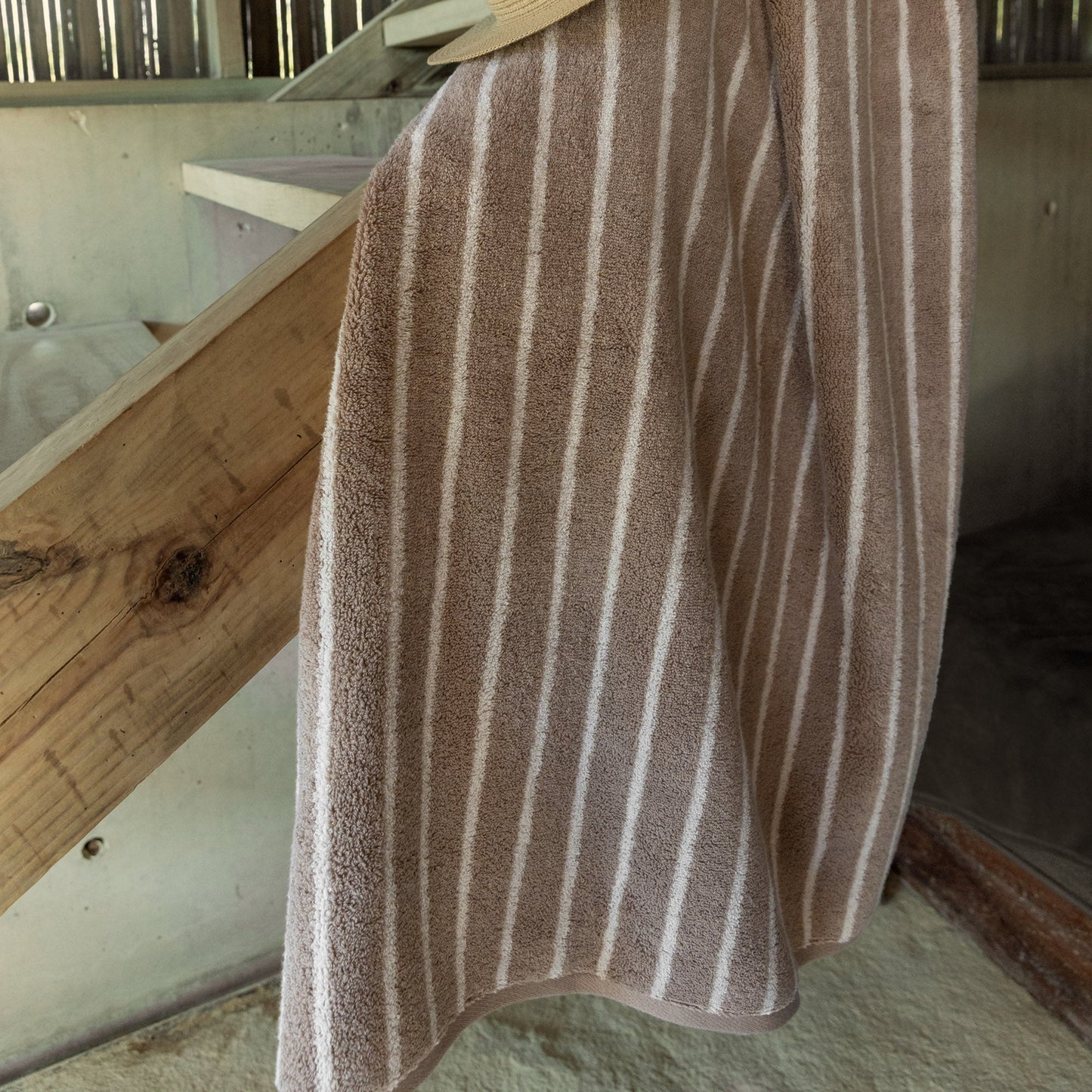 Striped bath towel in dark and light tones, plush terry with vertical bands.