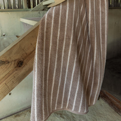 Striped bath towel in dark and light tones, plush terry with vertical bands.