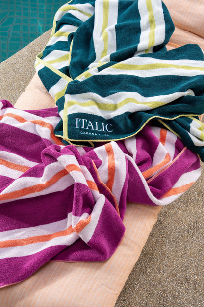 Cotton beach towel with purple-magenta and white striped bands, folded