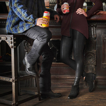 Black cowboy boots worn indoors, side profile with textured finish and heels