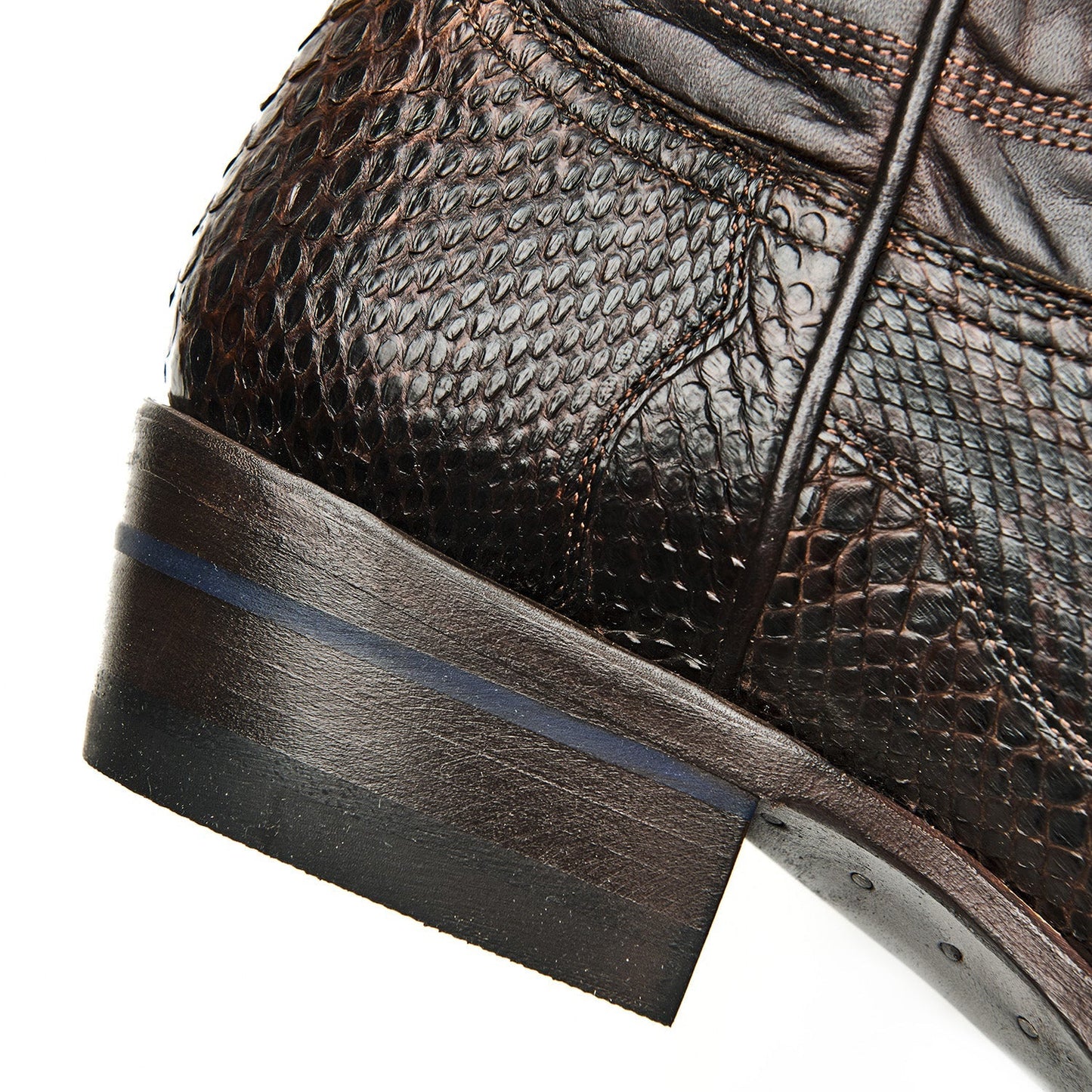Brown leather cowboy boot quarter and heel with scale texture and dark sole