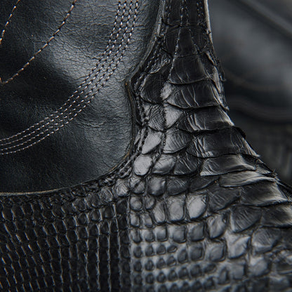 Black cowboy boot ankle close-up with crocodile texture and stitched seam detail