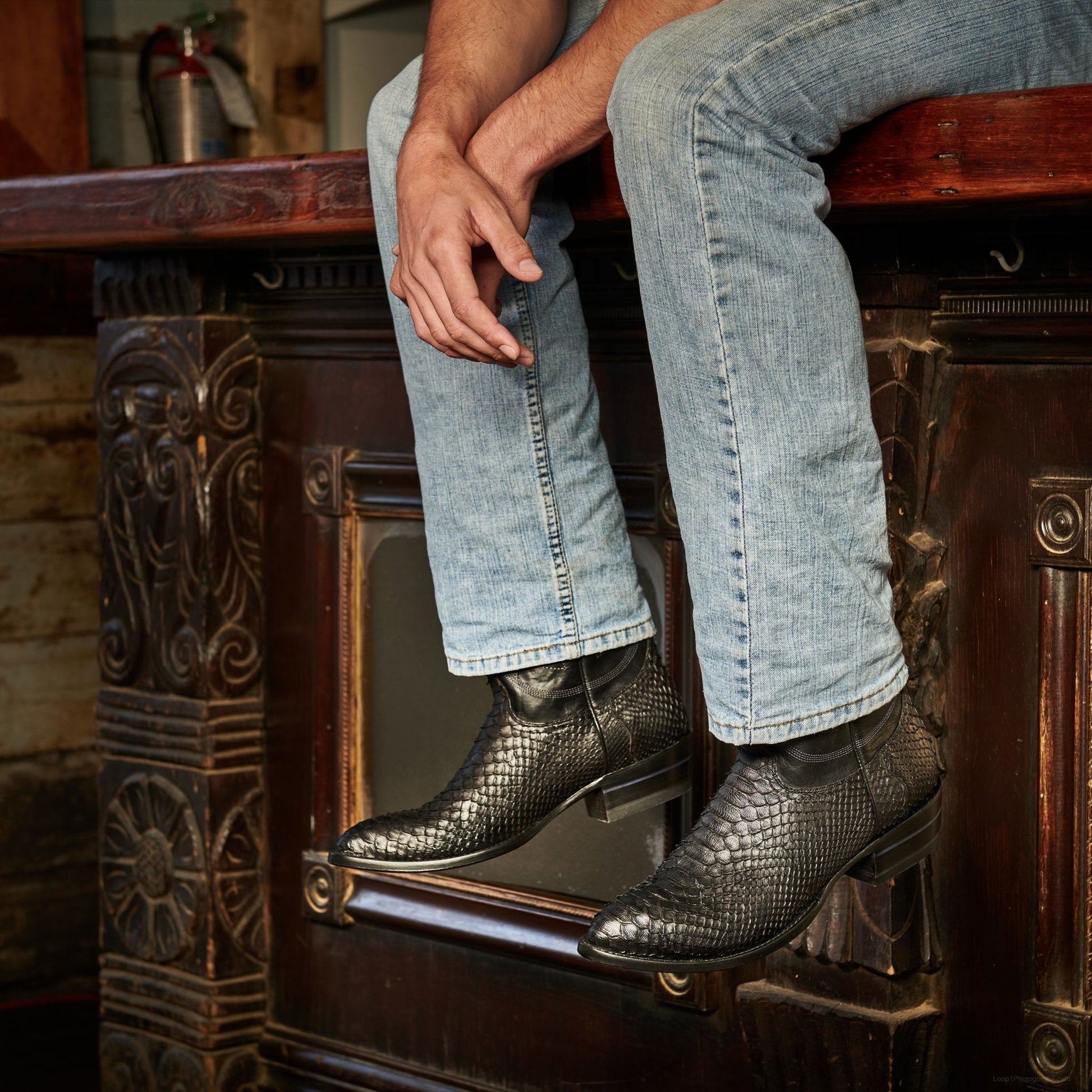 Black cowboy boots with textured leather, worn while stepping with jeans