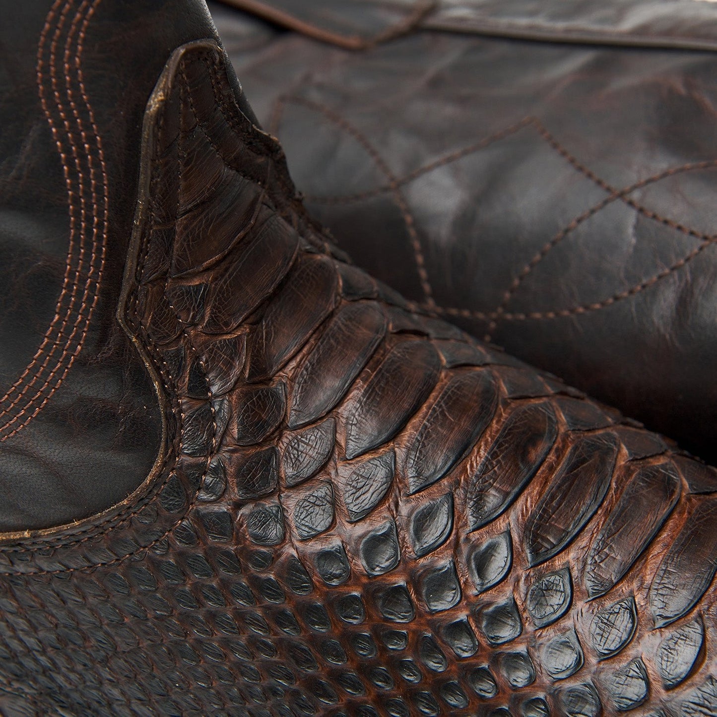 Brown leather cowboy boot instep with scale texture and decorative stitched panel