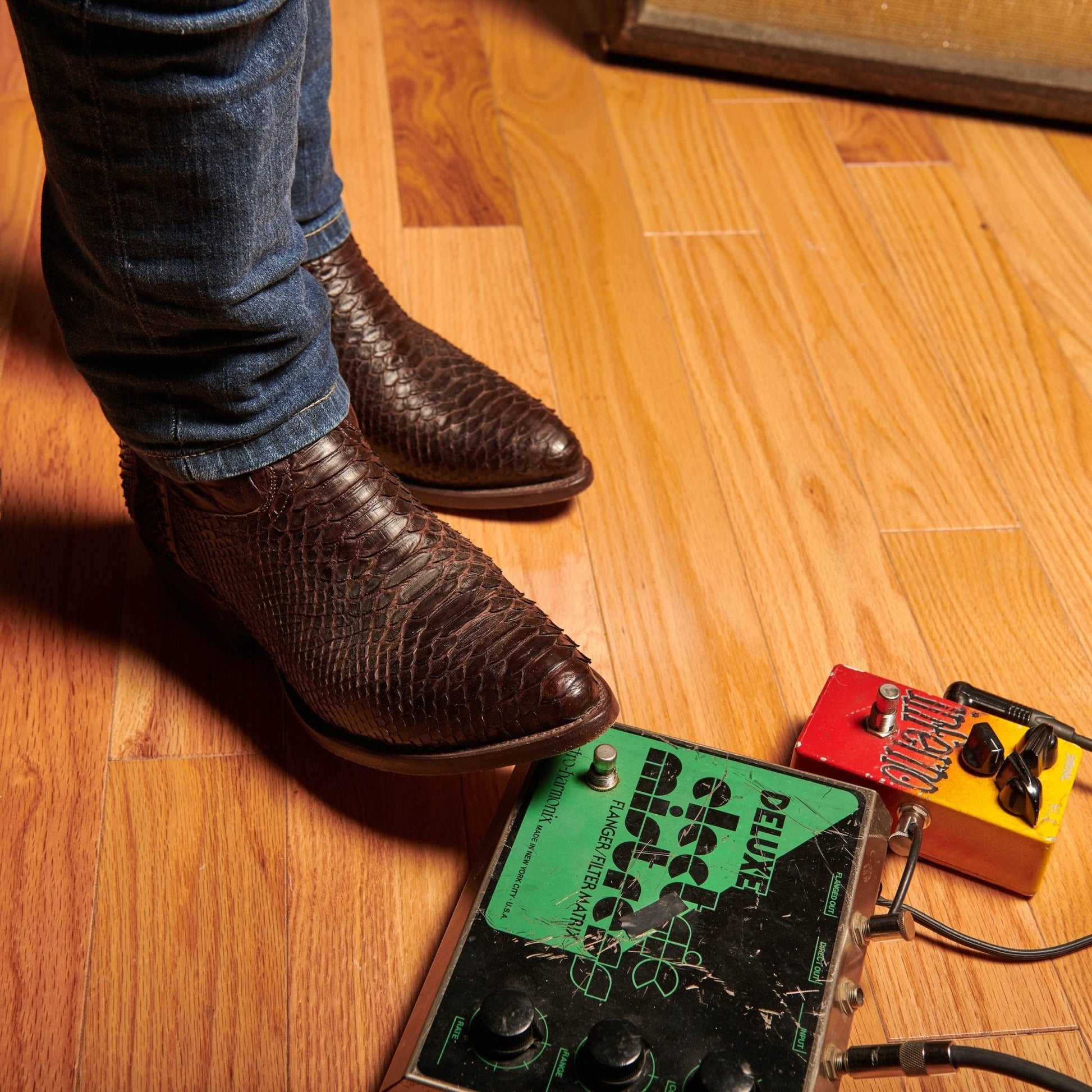 Brown cowboy boots standing on floor, showing crocodile-style texture and stitched seams