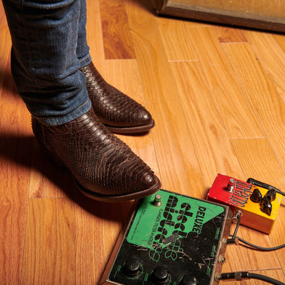 Brown cowboy boots standing on floor, showing crocodile-style texture and stitched seams